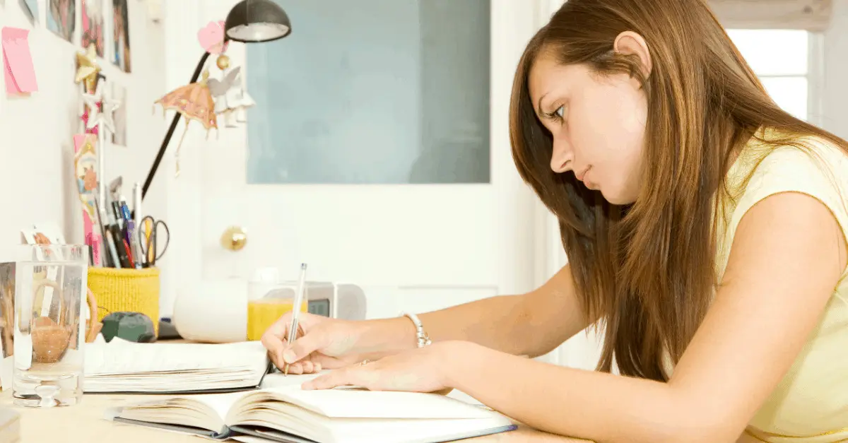 Teen writing in a book to submit her work for writing jobs