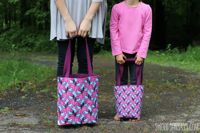 mother and daughter holding a pink tote bag each.