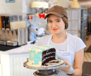Teenager working at a cafe, holding a cake - Jobs that Hire at 15